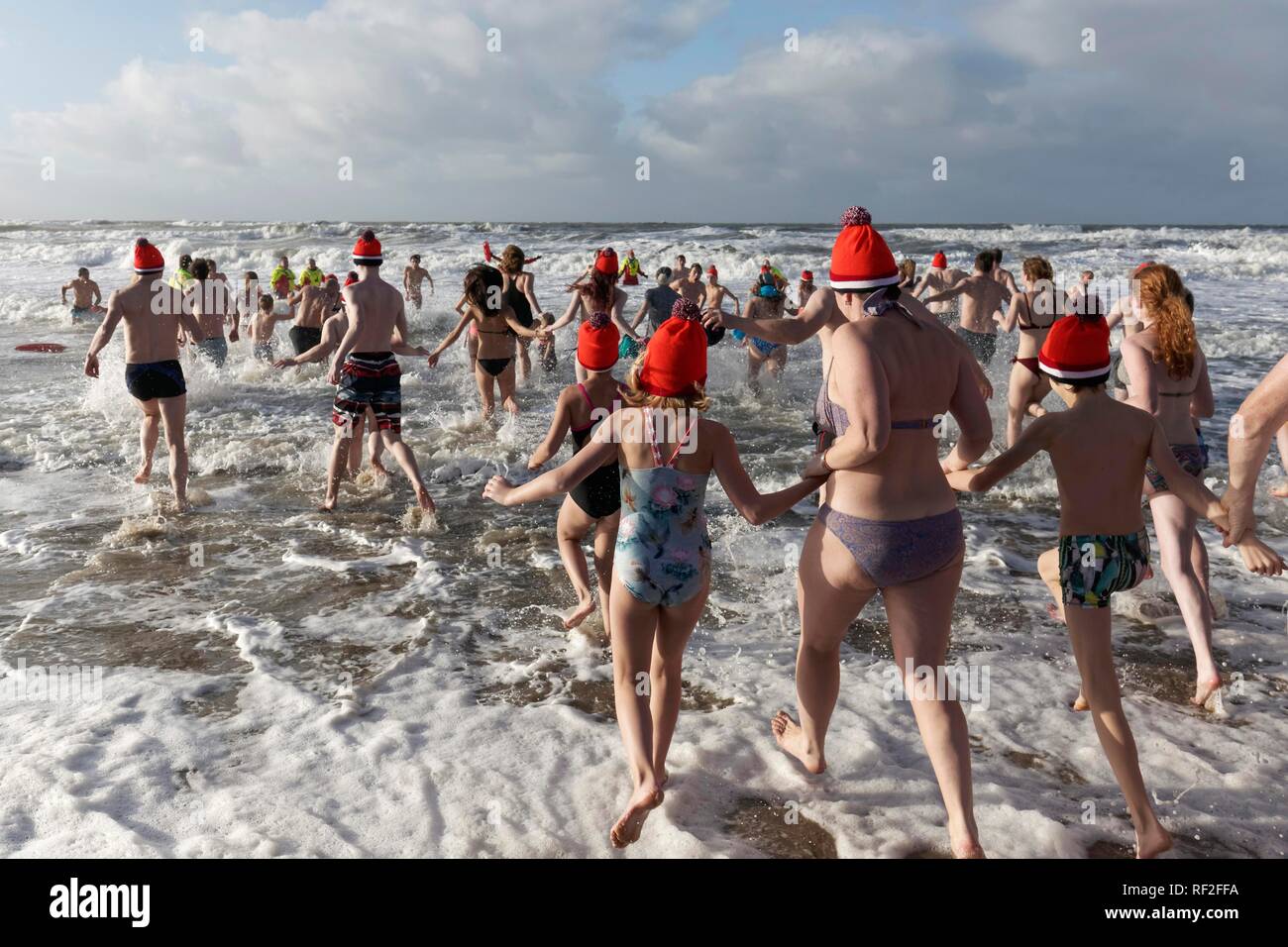 Muchas personas en traje de baño y gorros de Navidad en el mar frío en invierno, Año Nuevo, natación, Mar del Norte, Bergen aan Zee Foto de stock