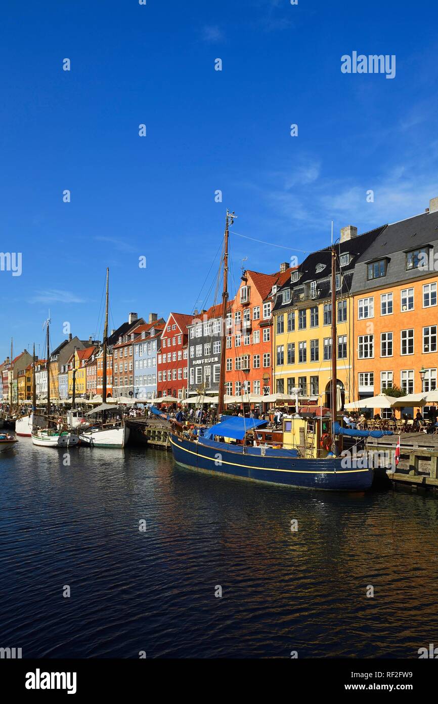 Veleros en el canal, en frente de la casa de coloridas fachadas, distrito de entretenimiento, Nyhavn, Copenhague, Dinamarca Foto de stock