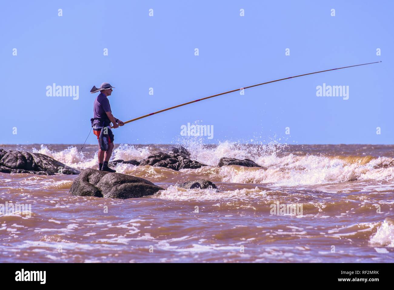 Pescador en las olas del río de la Plata, Playa Rambla, Montevideo, Uruguay Foto de stock