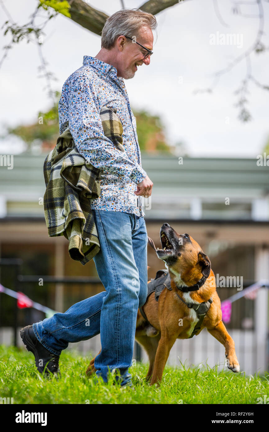 Un hombre con su perro ladrando en el parque en un perro mostrar Foto de stock