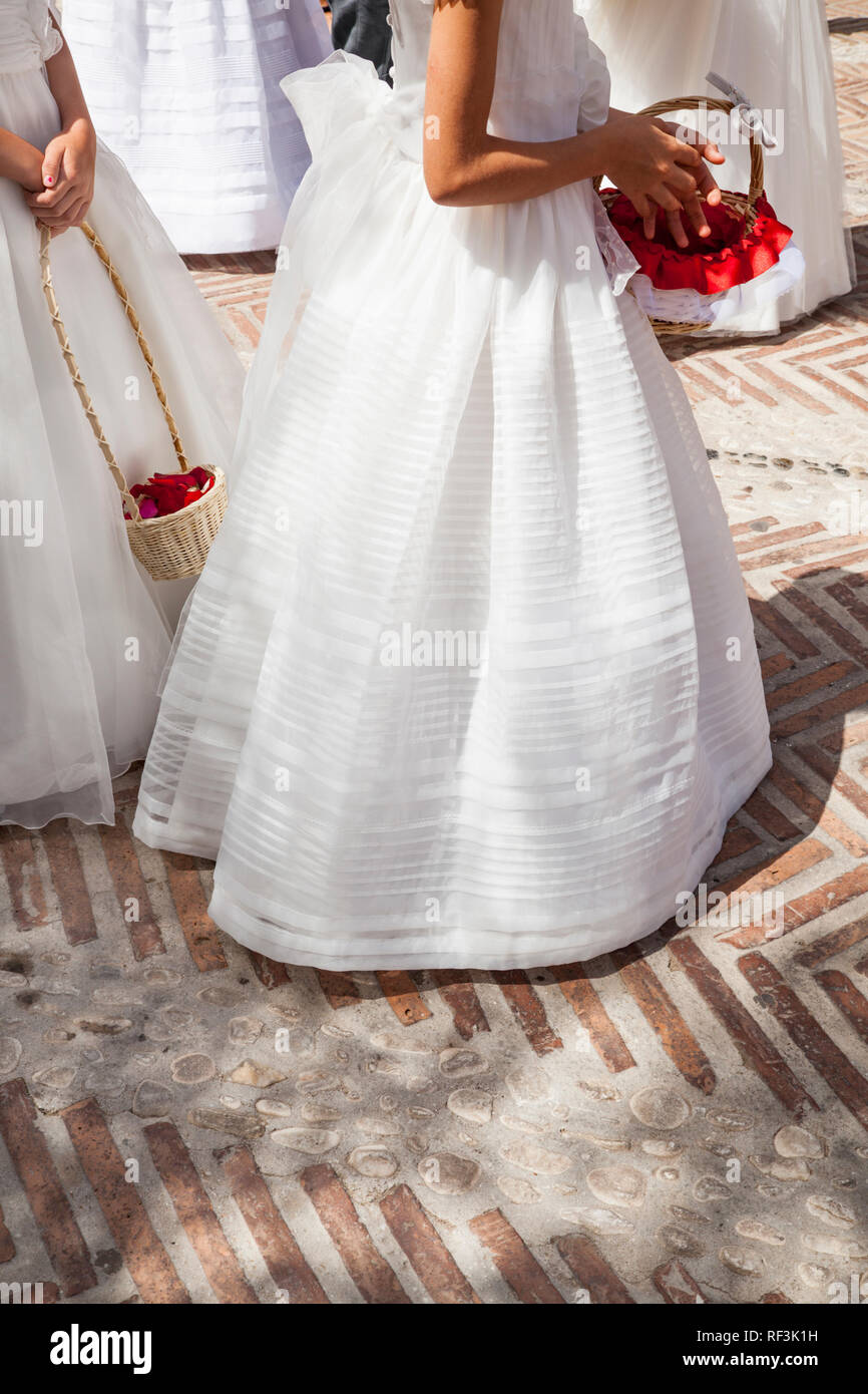 Las niñas vestidas de blanco y largos vestidos comunión con el canasto con flores Fotografía de stock -