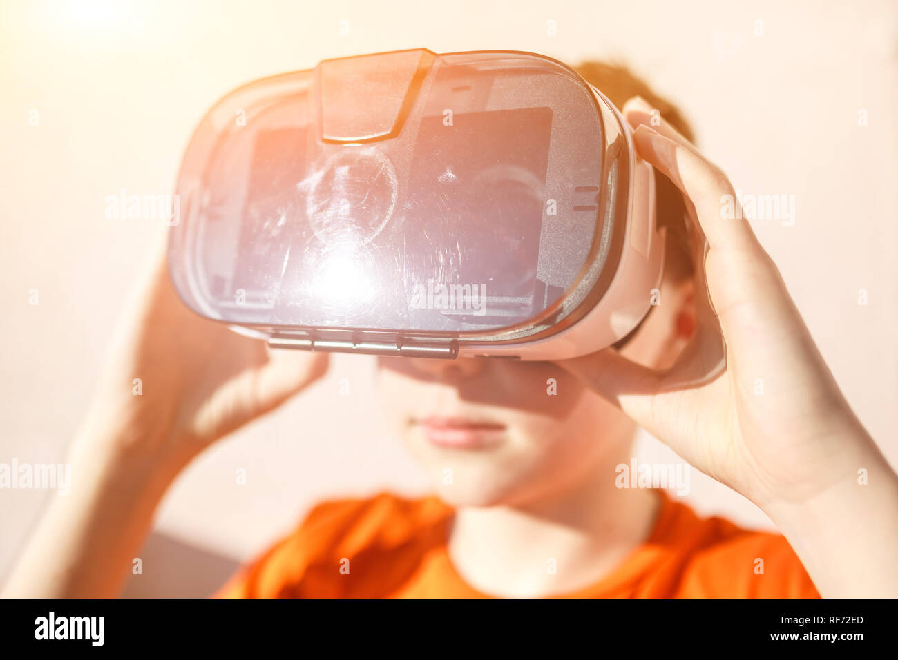 Chico en Orange t-shirt con VR AR 360 gafas de realidad virtual de cartón  para teléfono móvil jugando el juego. Dispositivo para ver películas de  viajes y en Fotografía de stock -