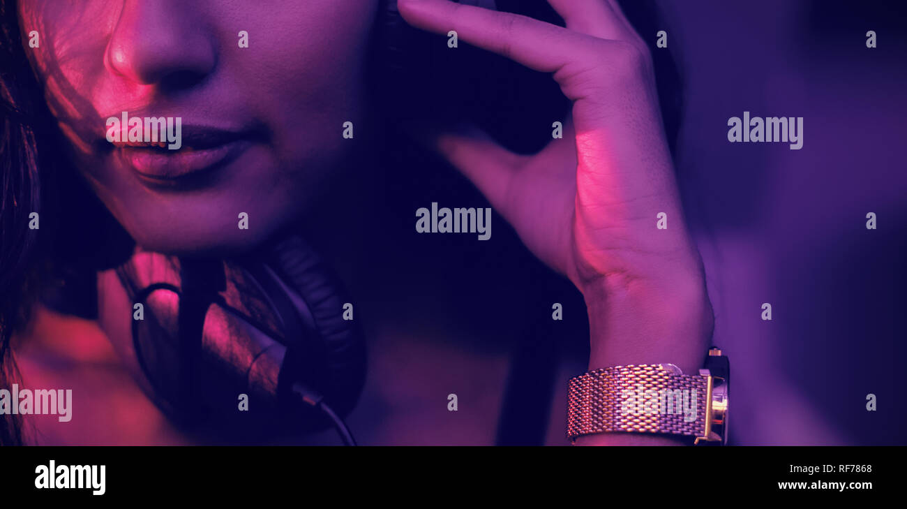 Dj femenina escuchando música en auriculares Foto de stock
