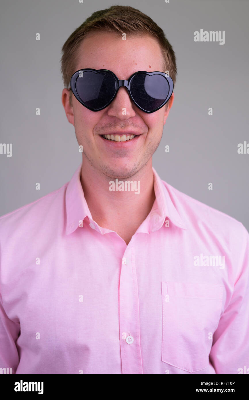Cara de joven empresario feliz sonriendo mientras llevaba gafas de sol con forma de corazón Foto de stock