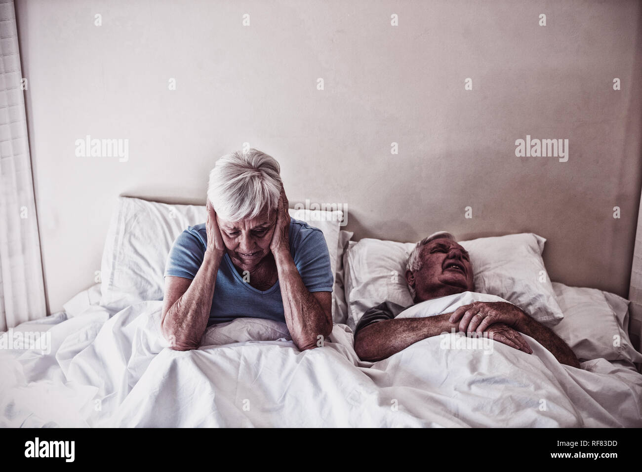 Mujer mayor obtención perturbado con el hombre ronquidos en la cama Foto de stock
