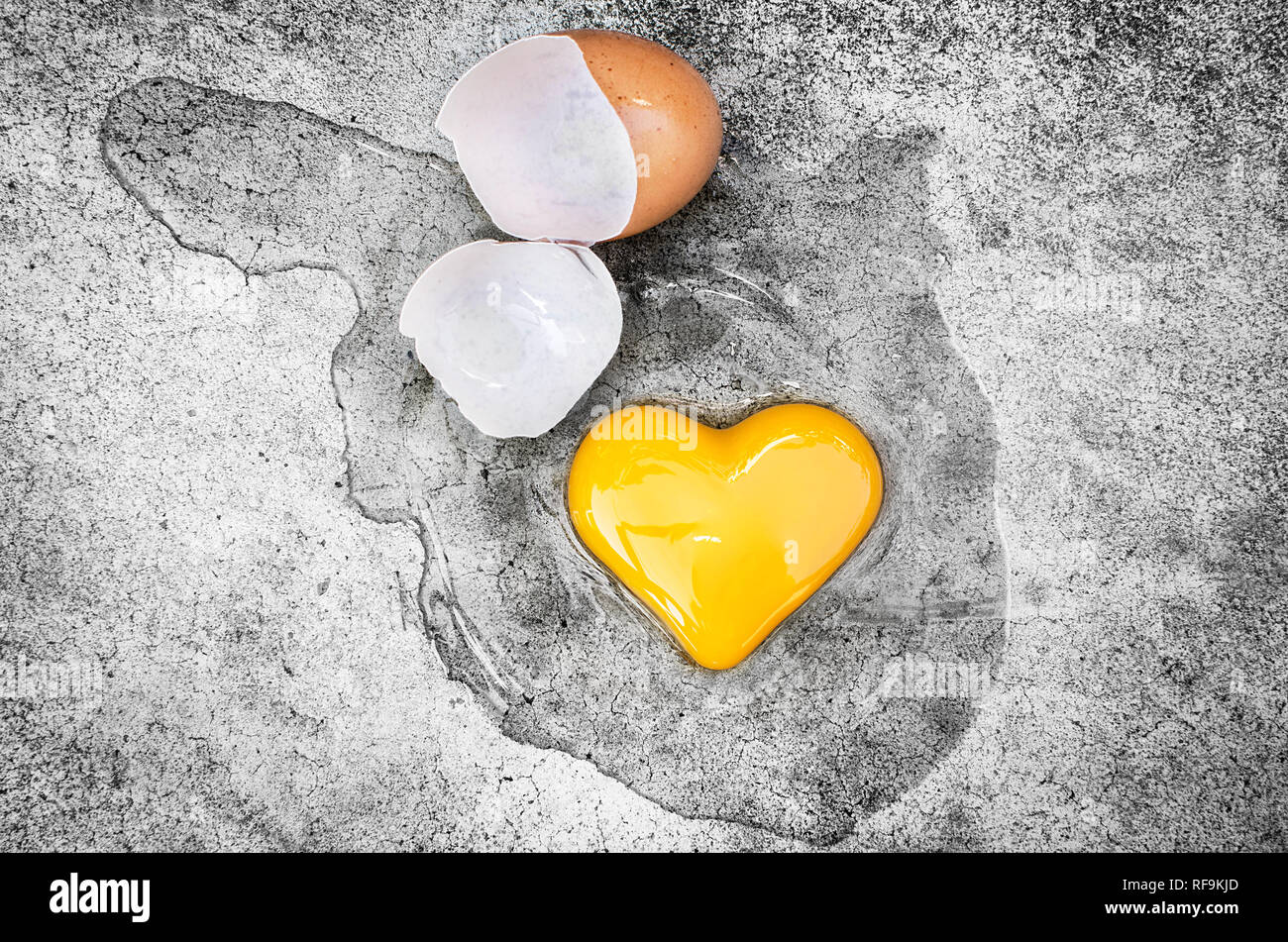 Forma corazón de yema de huevo con las cáscaras de los huevos en el suelo. Concepto de San Valentín Foto de stock