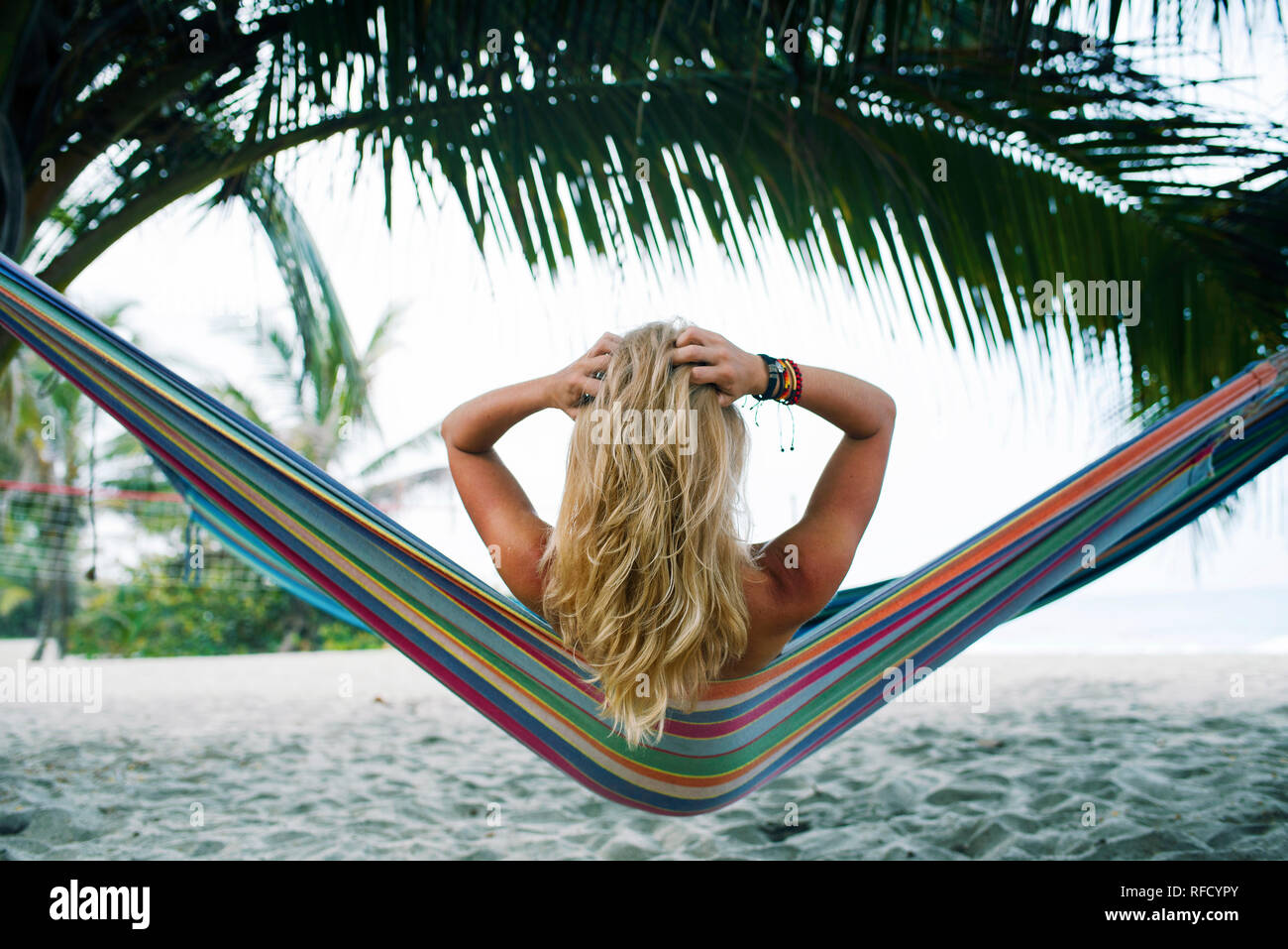 Vista trasera de las mujeres jugando con sus cabellos en una hamaca en la playa. Estilo de vida al aire libre / viajes concepto. Parque Tayrona, Colombia. Sep 2018 Foto de stock