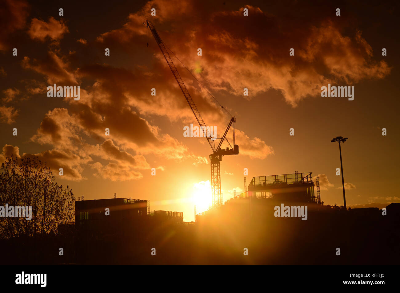 Grúa en sitio de construcción al atardecer sobre el horizonte de la ciudad de Leeds, Yorkshire, Reino Unido Foto de stock