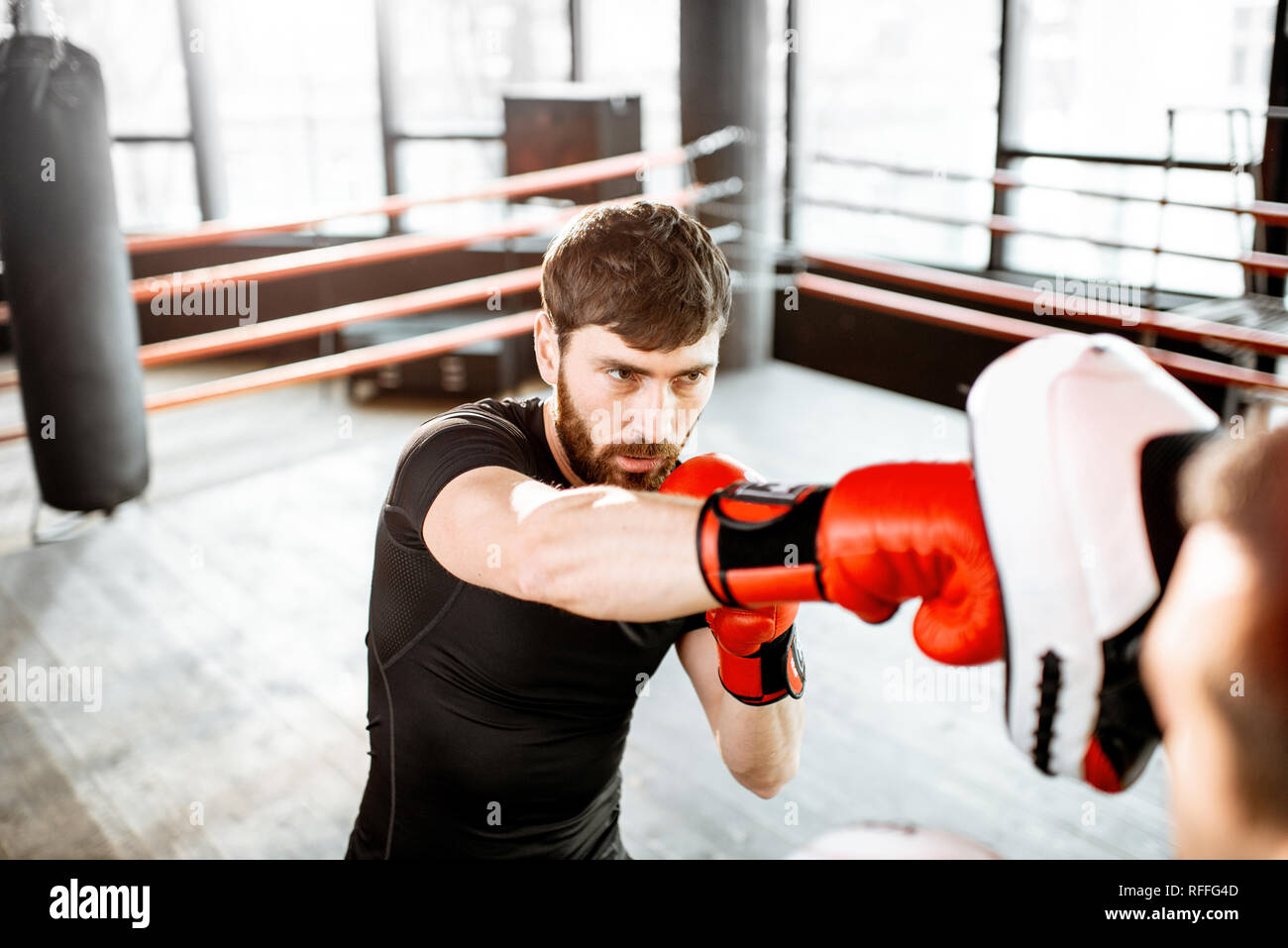 Athletic hombre combates durante la capacitación con instructor de boxeo en el cuadrilátero de boxeo en el gimnasio Foto de stock