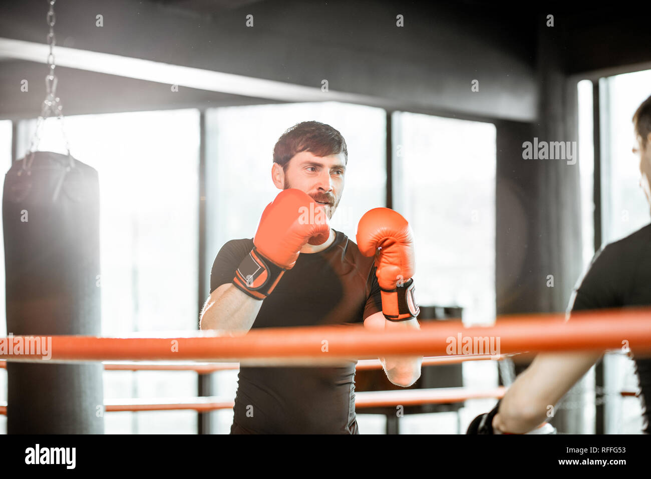 Athletic hombre combates durante la capacitación con instructor de boxeo en el cuadrilátero de boxeo en el gimnasio Foto de stock