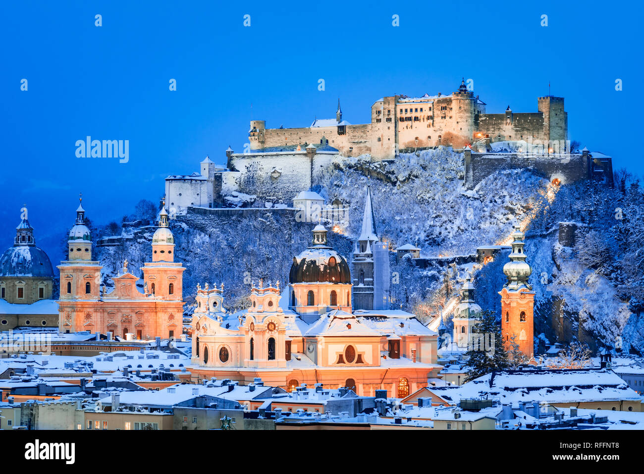 Salzburgo, Austria: Invierno lecturade la histórica ciudad de Salzburgo con la famosa Festung Hohensalzburg y el río Salzach iluminado en el hermoso crepúsculo Foto de stock