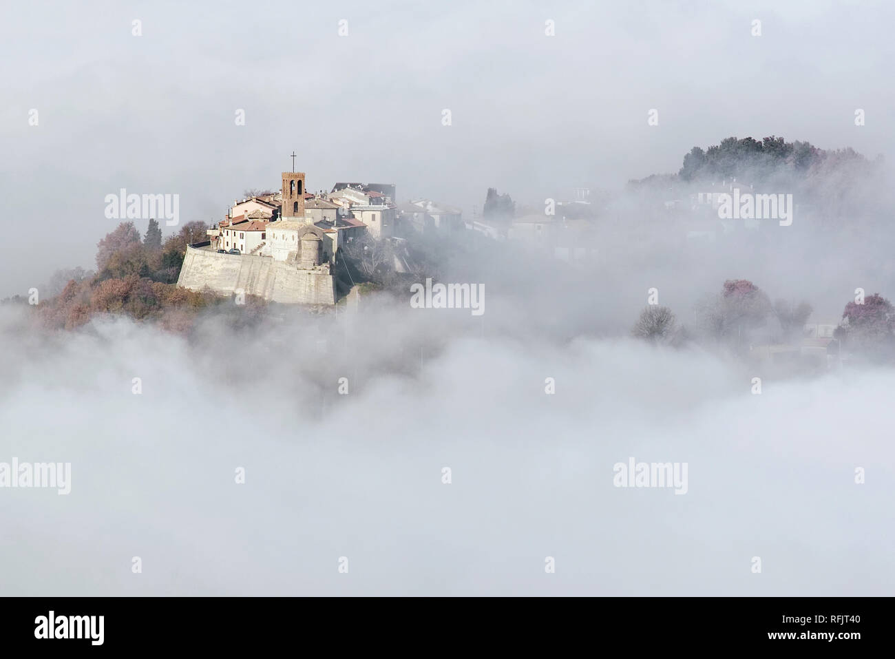 Pequeña aldea medieval surge de la niebla Foto de stock
