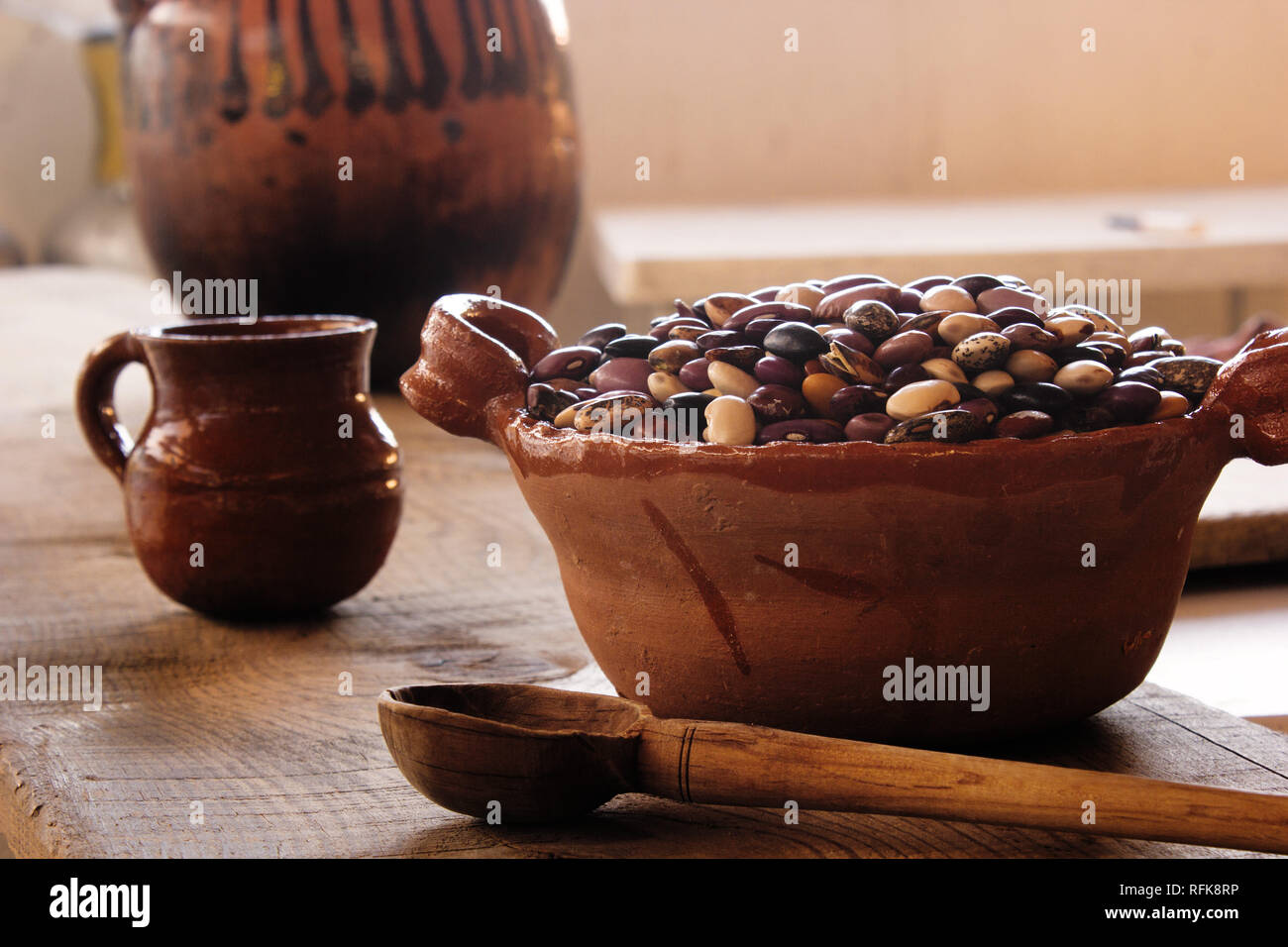 Olla de barro hechas a mano mexicano completo con una amplia variedad de  semillas de frijol, platos de arcilla mexicana sobre una tabla de madera  rústica vintage y cuchara Fotografía de stock -