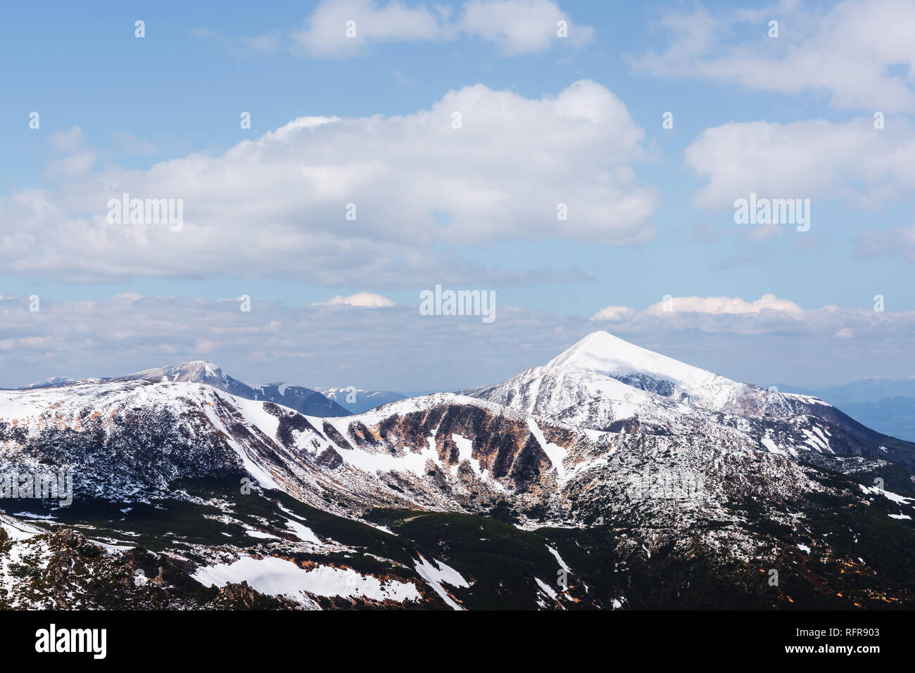 Vista de las colinas pedregosas con la nieve y el cielo azul. Dramática escena de primavera. Fotografía paisajística Foto de stock