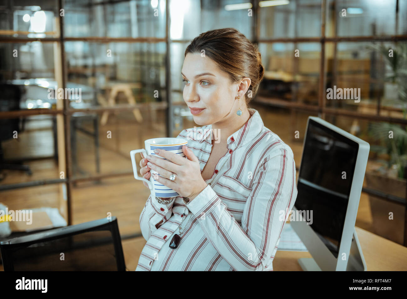 Atractiva mujer embarazada beber sabroso té caliente en la oficina Foto de stock