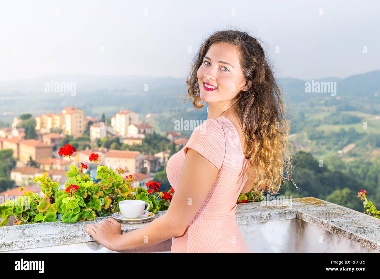 Taza de té café en el balcón terraza de geranio rojo flores fuera de Italia con vistas al paisaje urbano de Chiusi colinas de Toscana y Umbría cerca youn Foto de stock