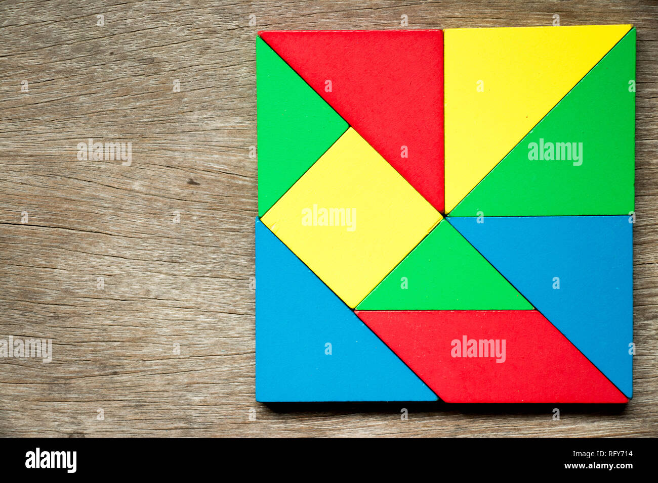 Colorido puzzle de juguete en forma de un cuadrado geométrico sobre fondo de madera Foto de stock