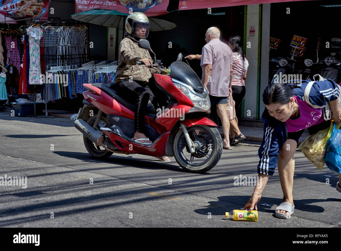 Mujer toma un riesgo para recuperar la botella bebidas con el resto del tráfico. Acción arriesgada. Tailandia Sudeste asiático Foto de stock