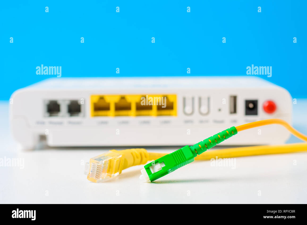 Fibra óptica y cables de red con el router inalámbrico de internet sobre  fondo azul Fotografía de stock - Alamy