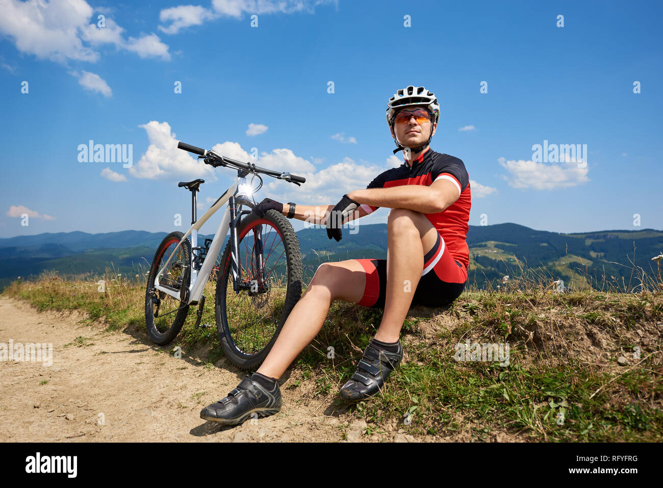 Joven deportista muscular ciclista profesional sportswear sentado cerca de  su bicicleta de carretera polvorienta descansando sobre hermosas montañas  verano backgro brillante Fotografía de stock - Alamy