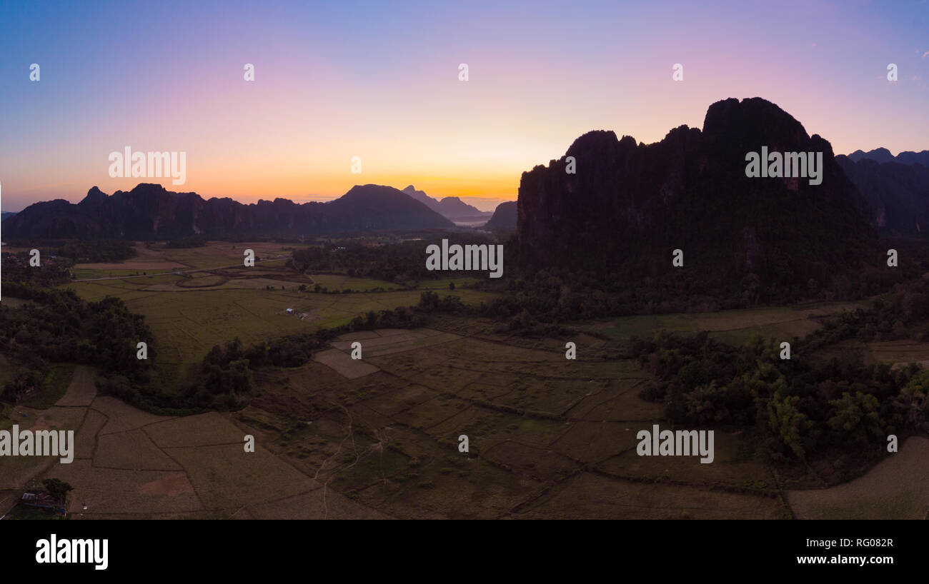 Antena: destino de viaje mochilero Vang Vieng, en Laos, en Asia. Atardecer en acantilados y pináculos de roca, arrozales Valley, un paisaje impresionante. Foto de stock