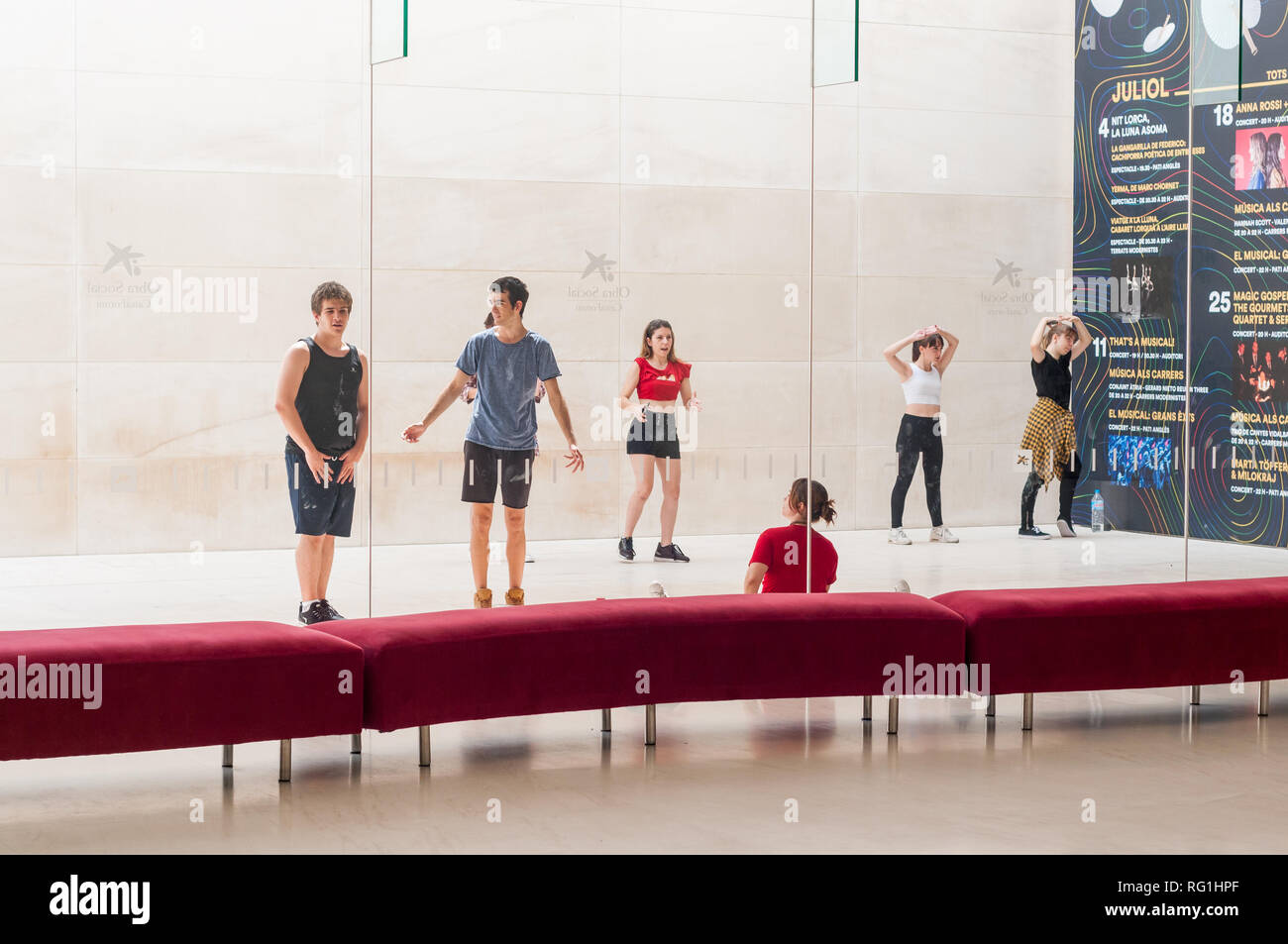 Niños y niñas bailando en frente de CaixaForum Barcelona Galería de arte, mirarse reflejado en el cristal, Barcelona, Cataluña, España Foto de stock