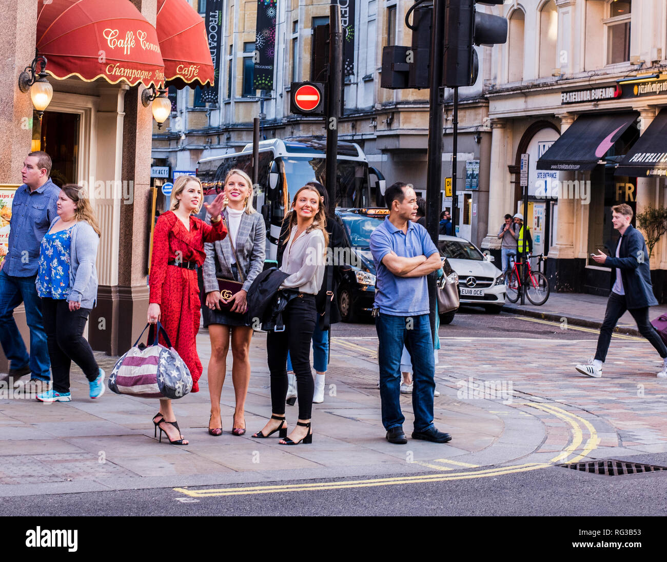 Amigas, de pie en la acera junto a carretera, decidir qué camino tomar, en el centro de Londres, Inglaterra, Reino Unido. Foto de stock
