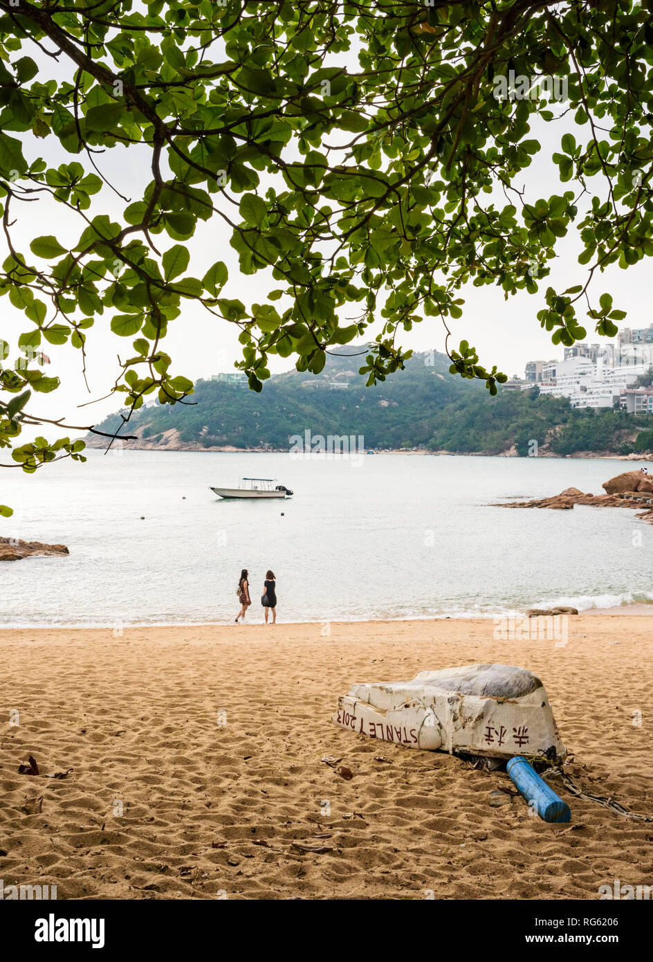 Dos mujeres miran las vistas al mar en la pequeña playa junto a Stanley, Hong Kong Foto de stock