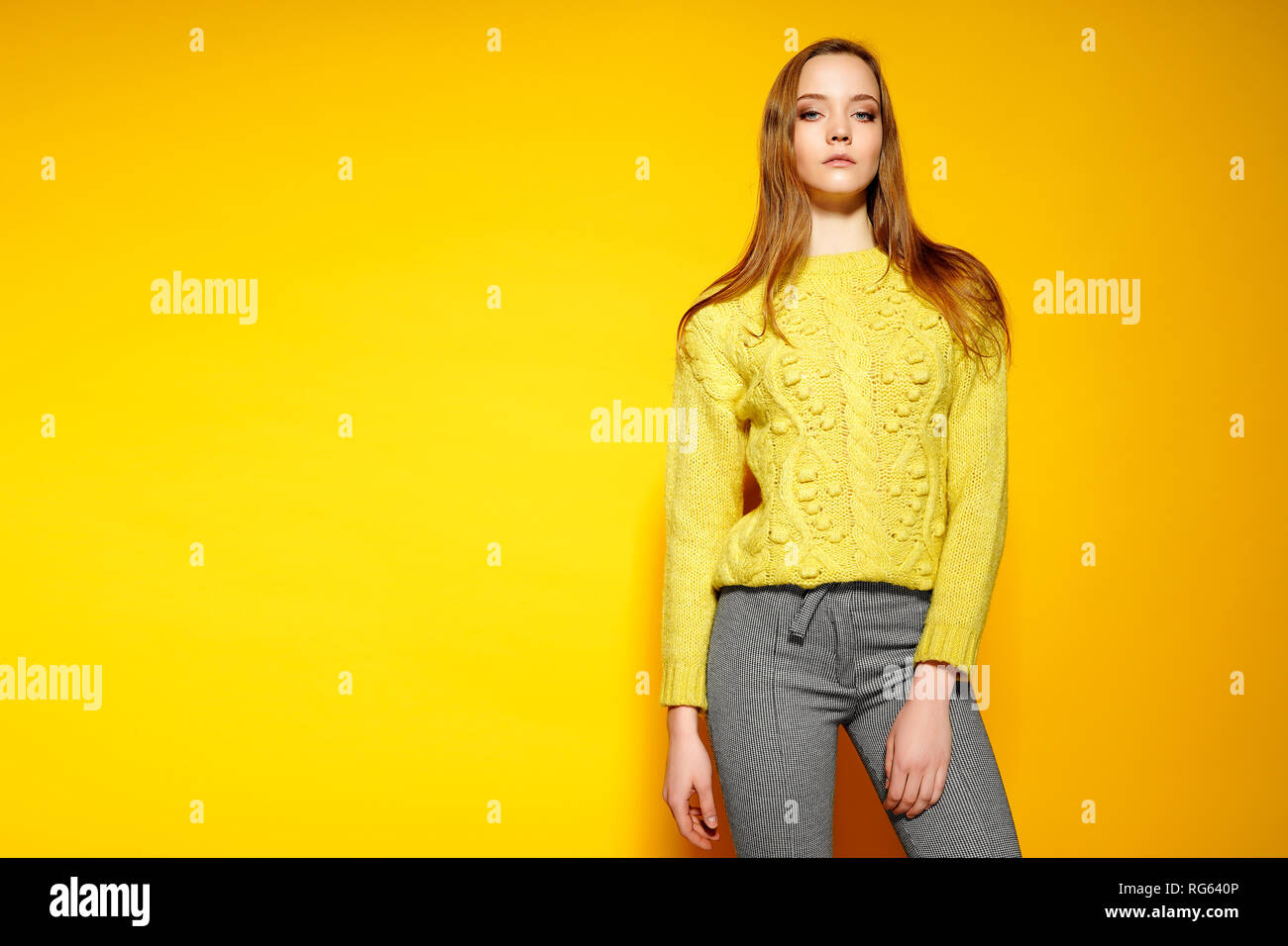 Modelo de mujer hermosa viste casual comfrotable suéter, gris plantea contra fondo de color amarillo. Mujer joven anuncia nuevo conjunto Fotografía de stock - Alamy