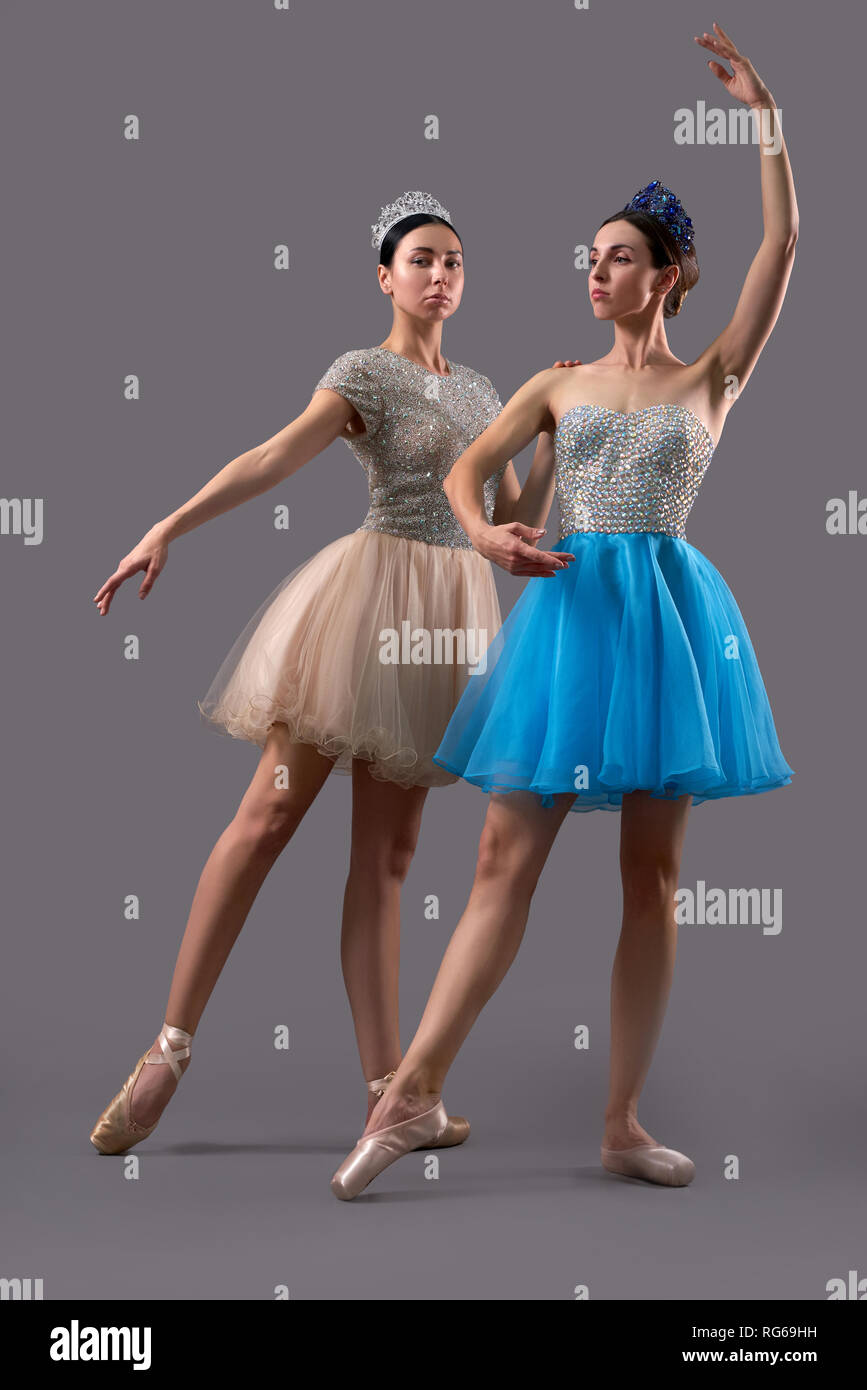 Dos bailarinas profesionales posando y bailando juntos en el estudio.  Bailarina en vestido azul sin dejar de lado mientras la mujer en beige  vestido mirando a la cámara. Concepto de ballet art