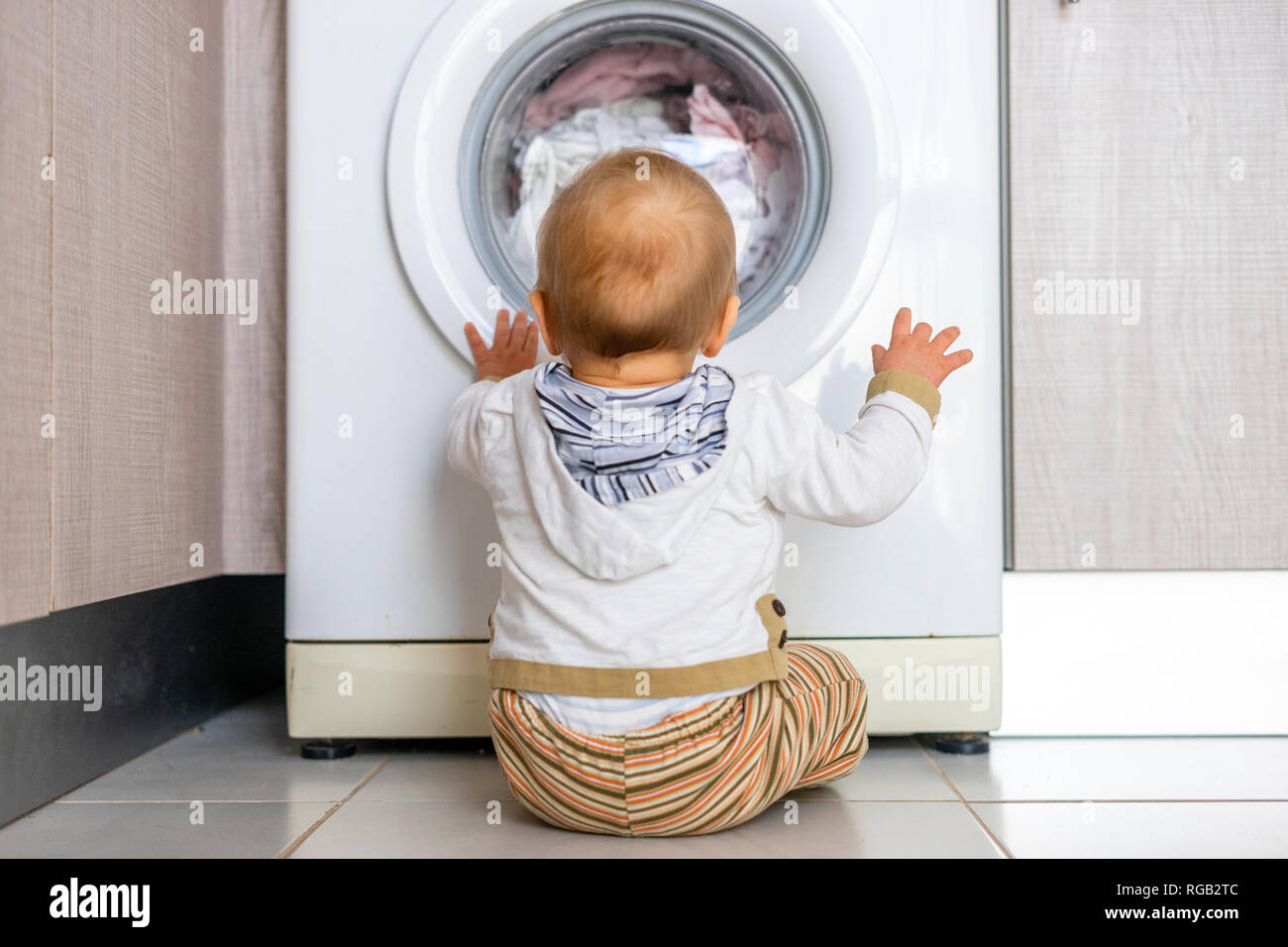Baby Boy interesados en los ciclos de la lavadora lavando ropa Foto de stock