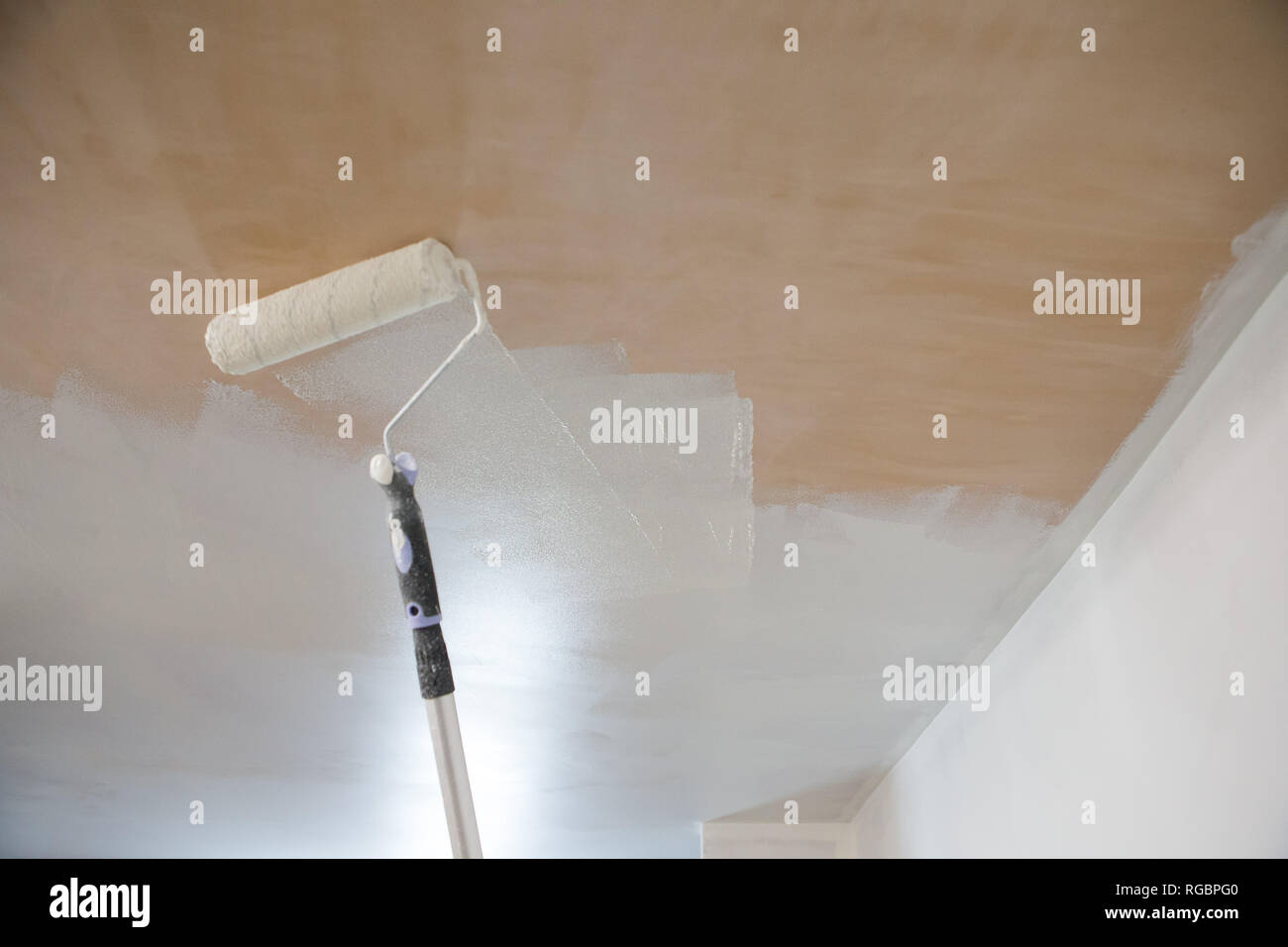 Rodillo para pintar una emulsión blanca se aplica a un techo de escayola  desnuda en una propiedad de nueva construcción Fotografía de stock - Alamy