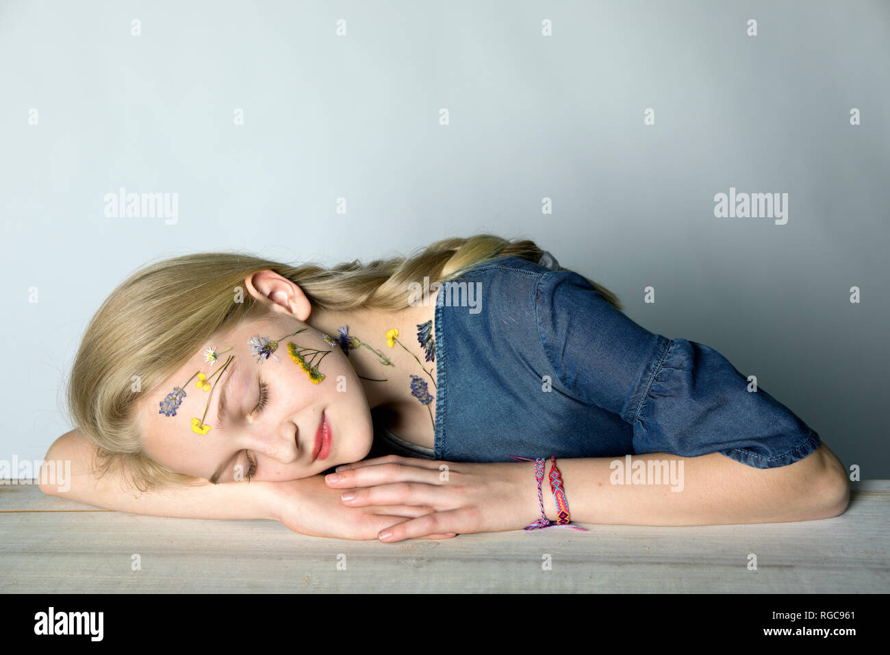 Retrato de chica rubia con tatuaje de flores presionado en su cara Foto de stock