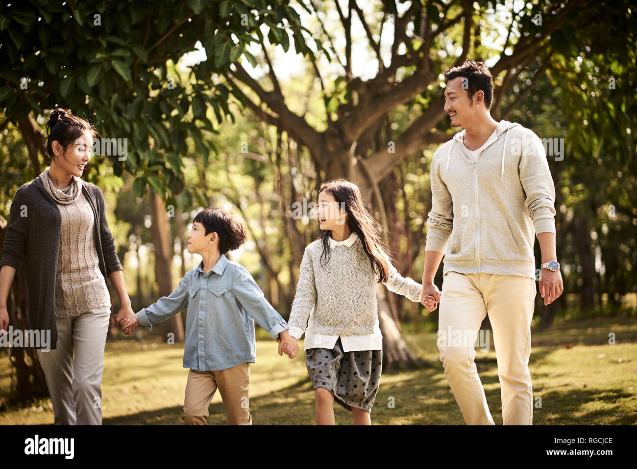 Familia con dos niños asiáticos relajantes paseos en el parque feliz y sonriente. Foto de stock