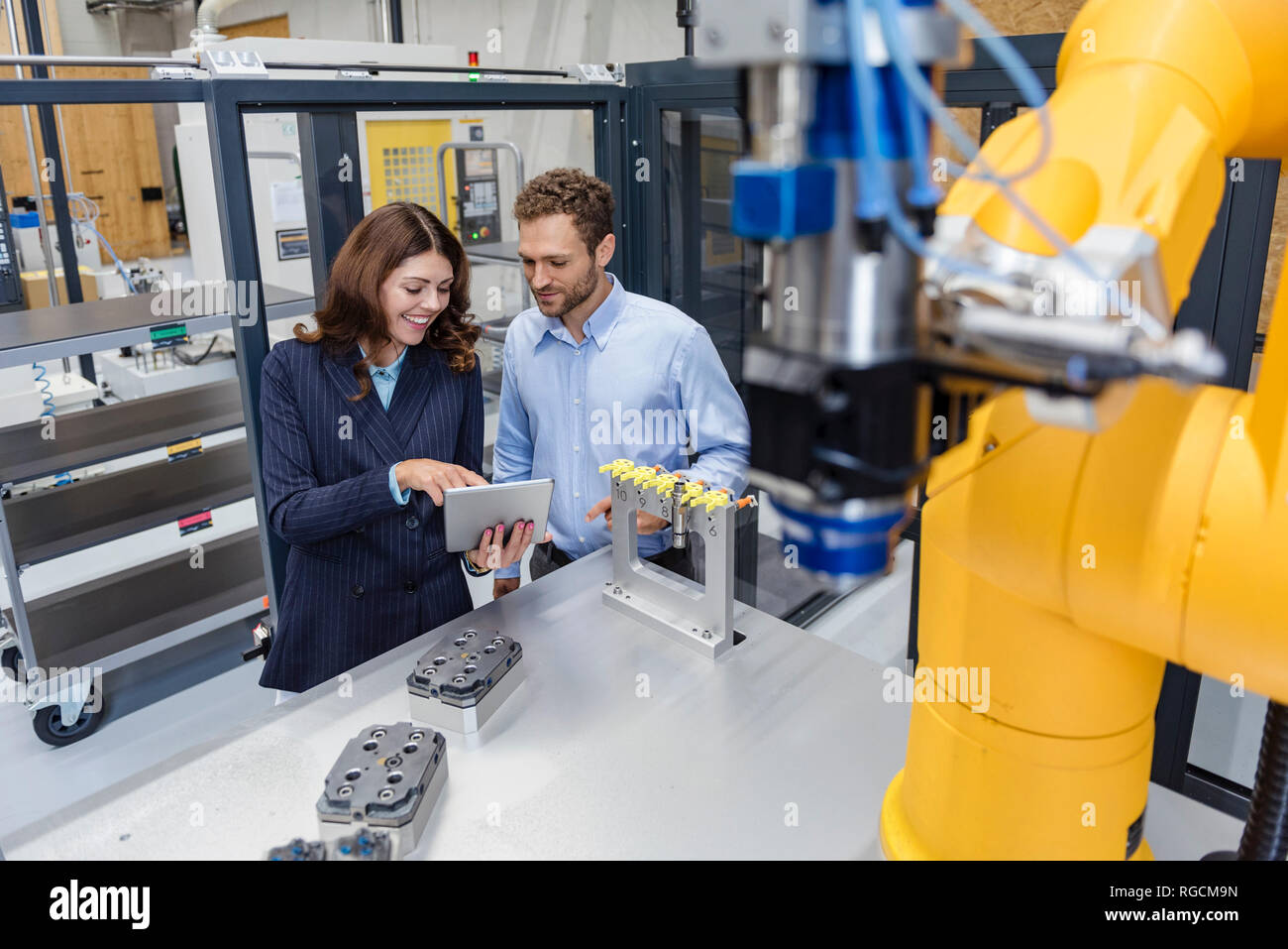 Sus colegas en la empresa de alta tecnología el control de robots industriales, mediante tableta digital Foto de stock
