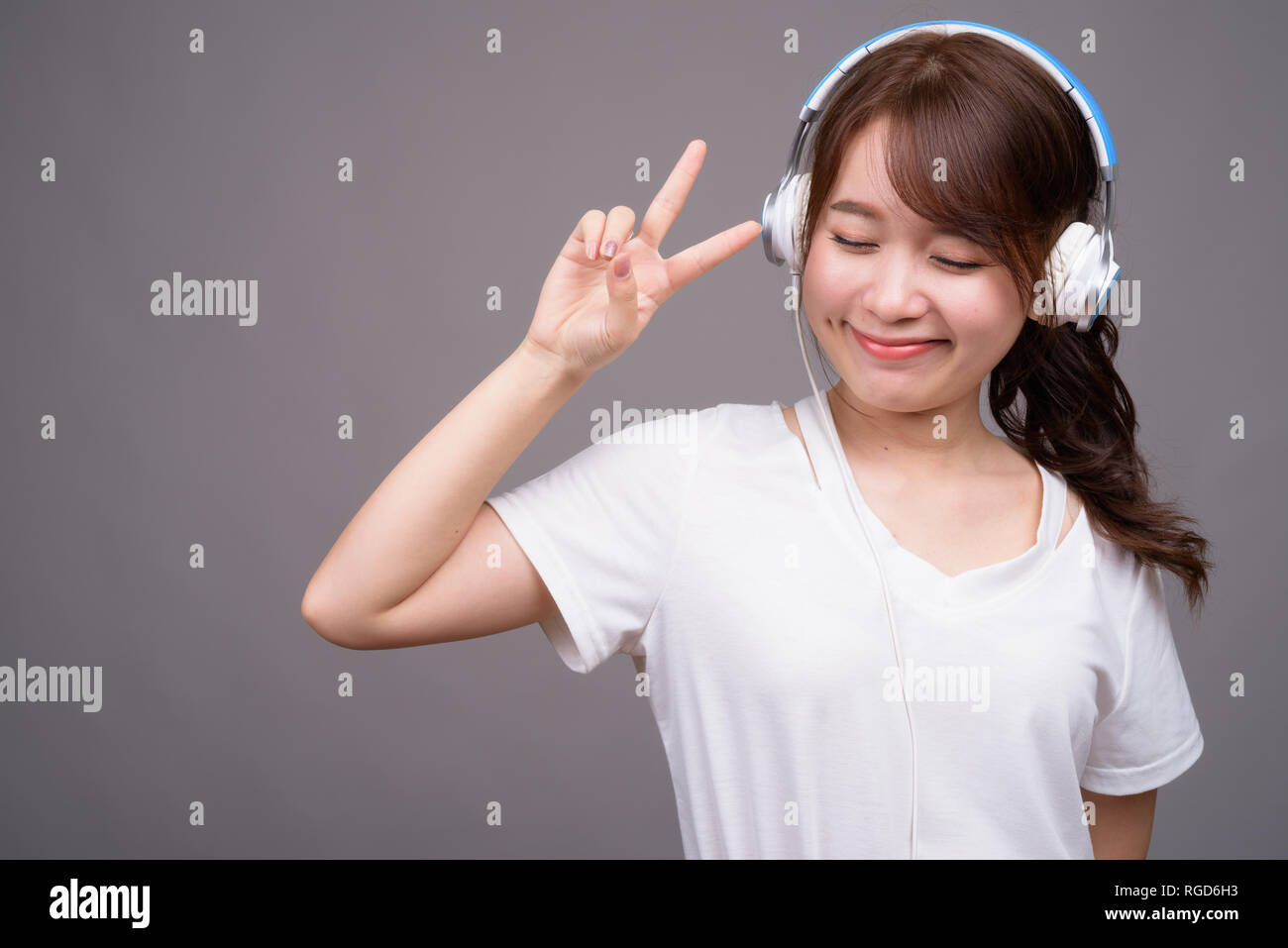 Hermosa joven mujer asiática usando audífonos para música Foto de stock