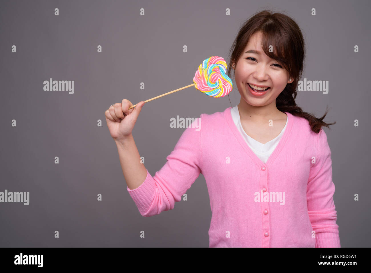 Hermosa joven mujer asiática sosteniendo coloridos lollipop Foto de stock