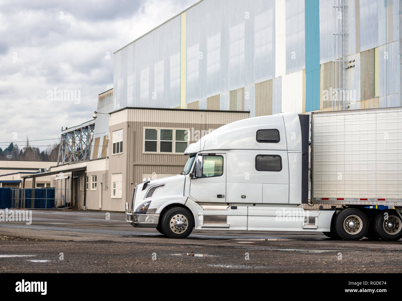 Big Rig blanca larga semi camión con cabina alta y reefer semi-remolque de pie en el aparcamiento esperando la carga y la posibilidad de continuar Foto de stock