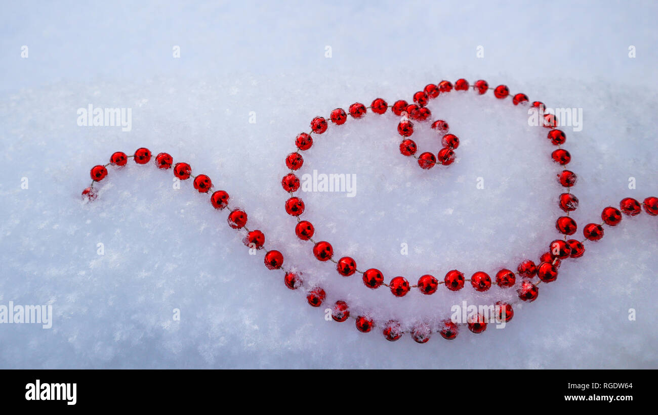 Perlas de color rojo brillante en forma de corazón en el blanco de la nieve fresca. Perfecto Día de San Valentín, Navidad, Año Nuevo fondo de tarjetas de felicitación. Foto de stock
