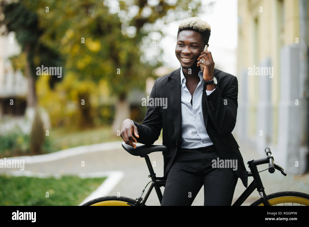 Retrato de un joven apuesto a través de teléfono móvil y el piñón fijo de bicicleta en la calle. Foto de stock