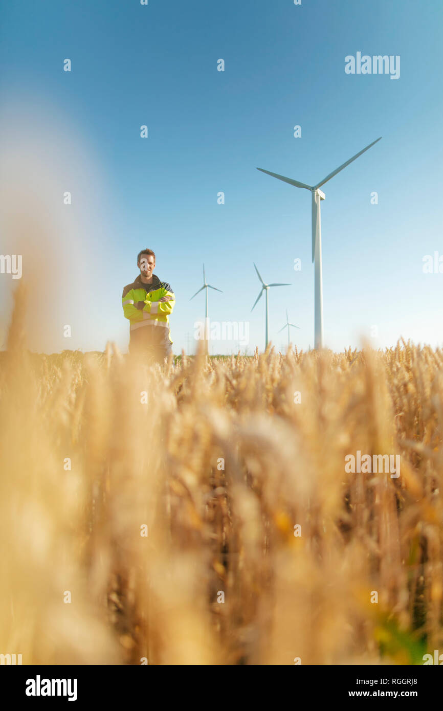 Retrato del ingeniero sonriendo de pie en un campo en un parque eólico Foto de stock