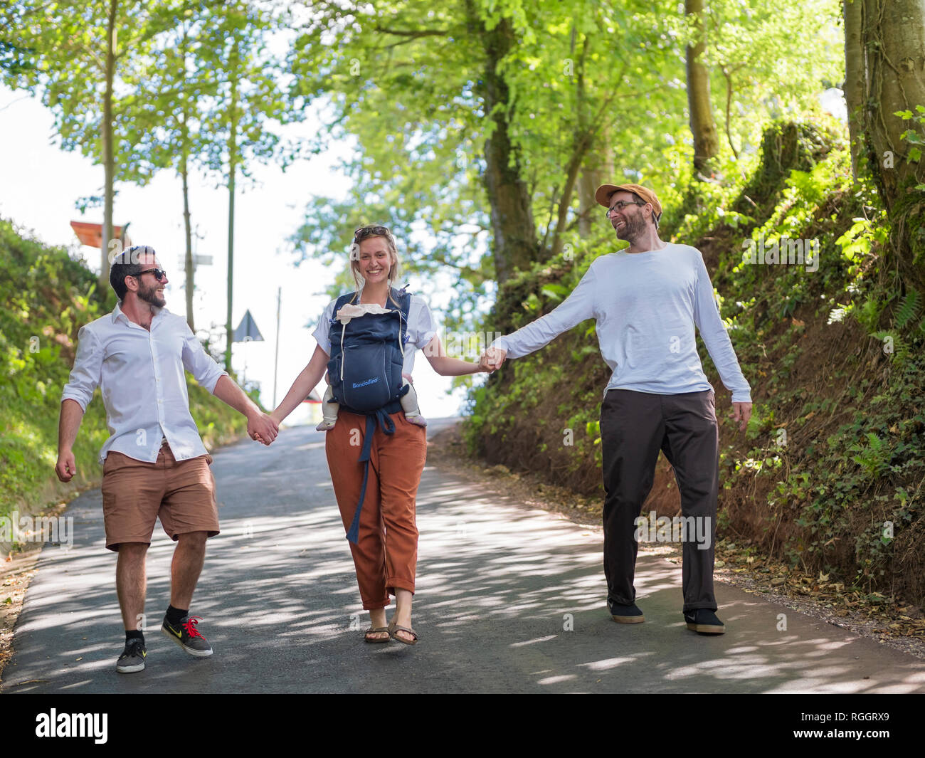 Felices padres con niña paseando de la mano con un amigo Foto de stock