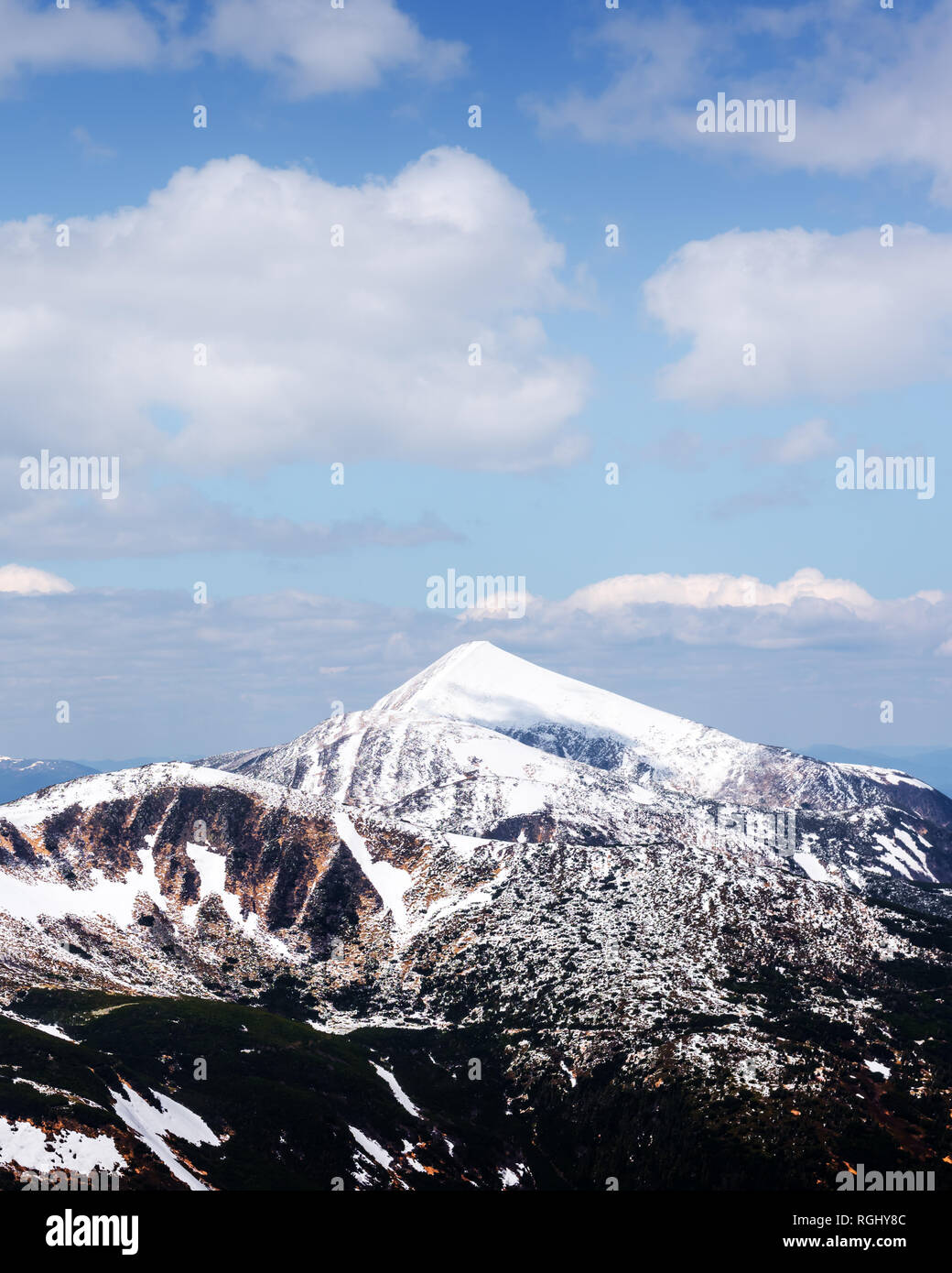 Vista de las colinas pedregosas con la nieve y el cielo azul. Dramática escena de primavera. Fotografía paisajística Foto de stock