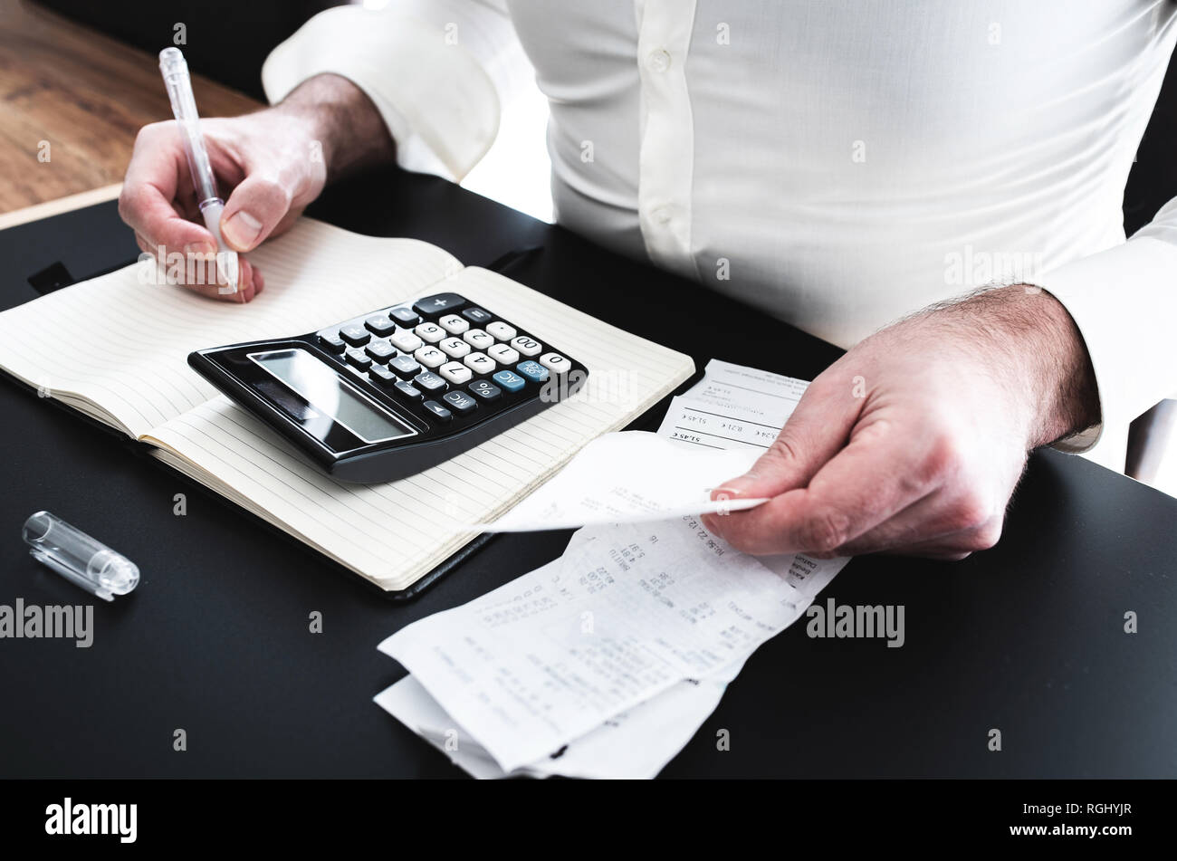 Hombre y escritorio con calculadora, facturas o recibos de ventas y notpad Foto de stock