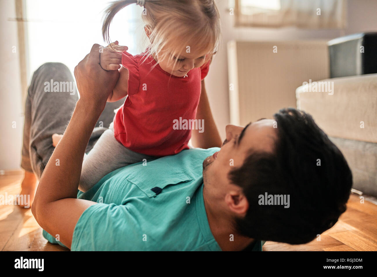 Niña jugando con su padre en casa Foto de stock