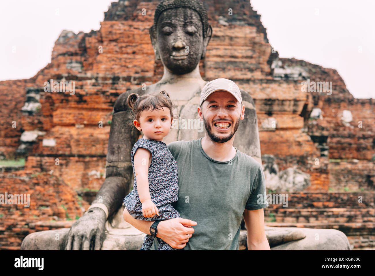 Tailandia, Ayutthaya, Retrato de padre e hija sonriente a una estatua de Buda en Wat Mahathat Foto de stock