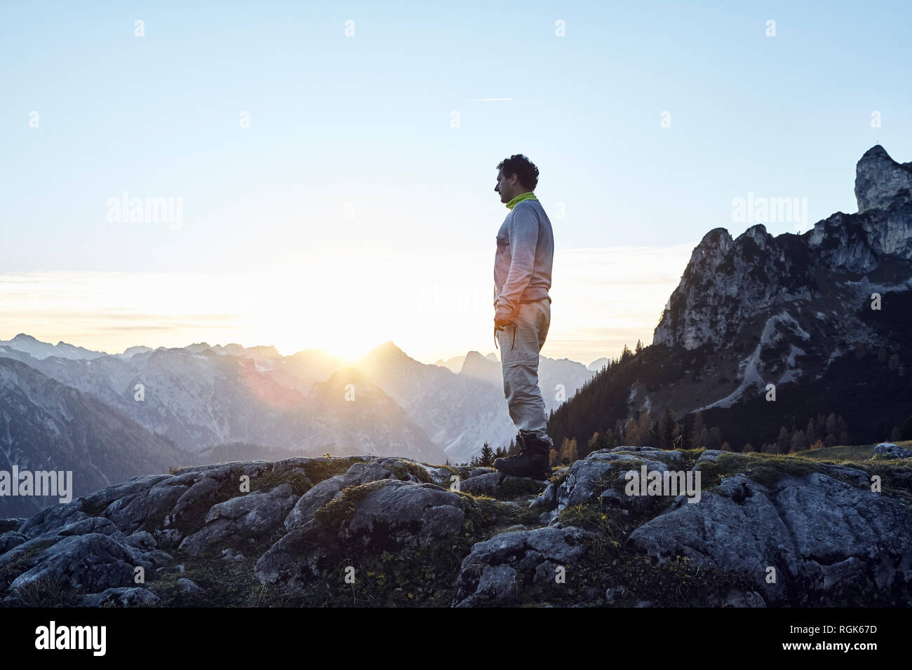 Austria, Tirol, montañas Rofan, caminante de pie sobre las rocas al atardecer Foto de stock