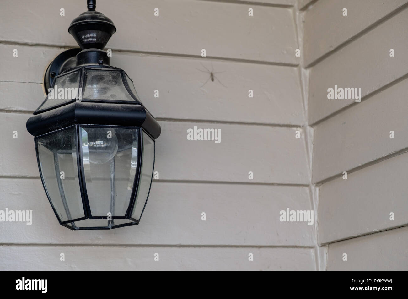 Puerta de hierro negro Vintage lámpara colgante con cristal adjunta al edificio shingled gris. Foto de stock