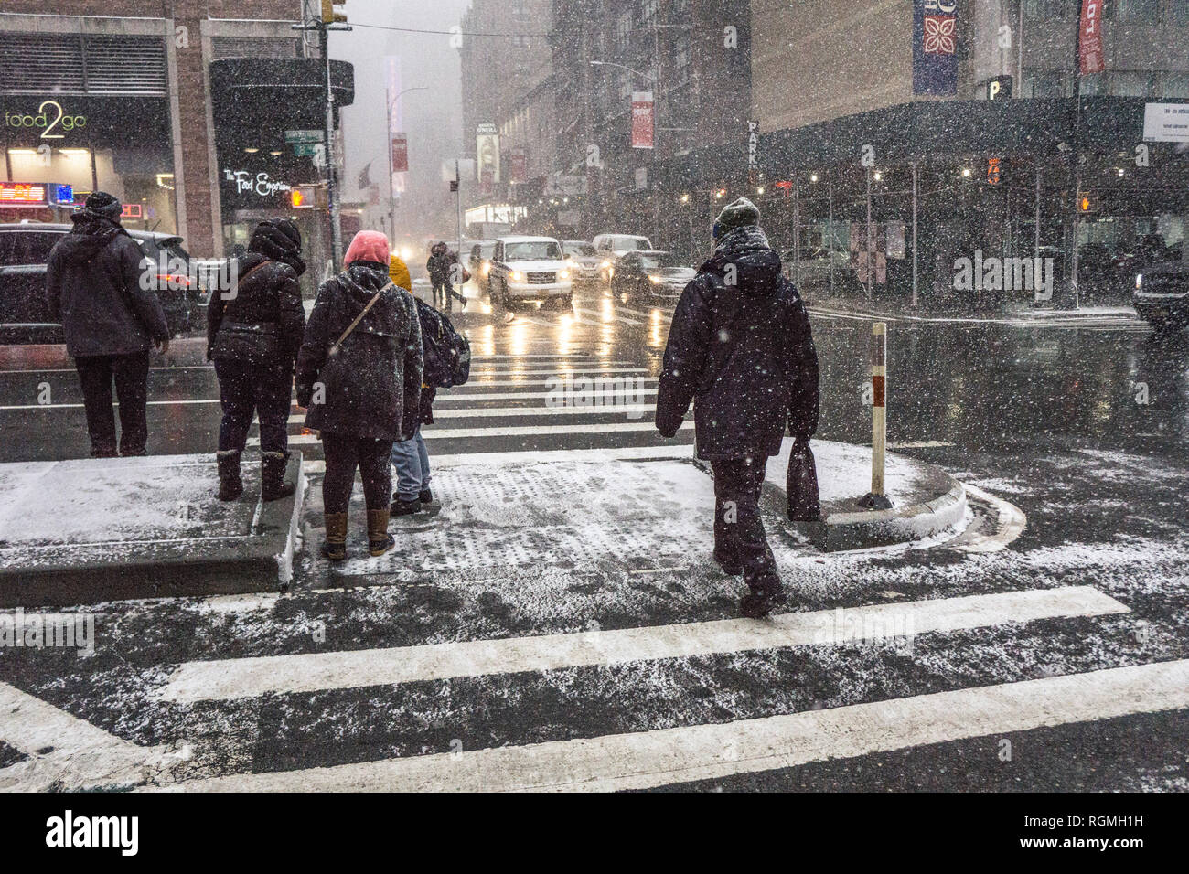 Nueva York, EE.UU. El 30 de enero de 2019; ver en la esquina de la 8ª Avenida y la calle 49 como peatones agacharse en el semáforo contra viento breve tarde impulsado snow squall. En general los neoyorquinos no llevar abrigos de pieles o en la calle cuando nieva, prefiriendo abajo parkas (que libre las piernas) con carcasas desgastadas por ver las tapas. Son abrigos de pieles y de Wall Street para caminar una breve distancia entre el vehículo y el edificio. Crédito: Dorothy Alexander/Alamy Live News Foto de stock