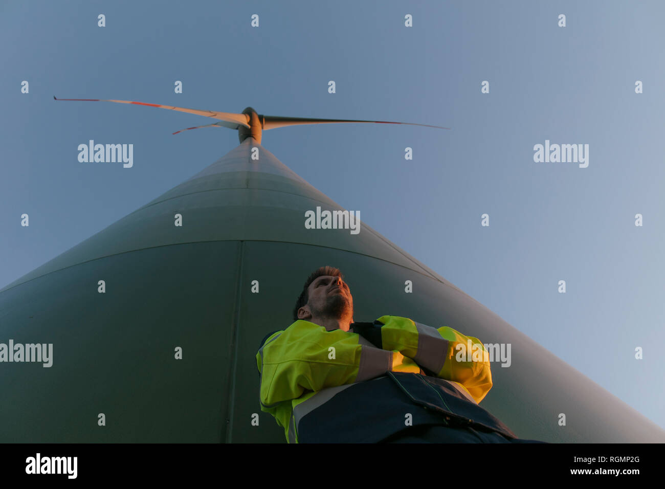 Ángulo de visión baja de un ingeniero de pie en un aerogenerador Foto de stock